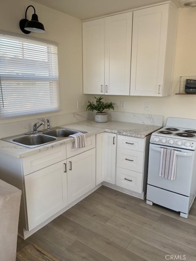 kitchen featuring white cabinets, light hardwood / wood-style floors, white range, and sink