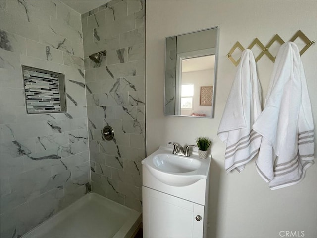 bathroom with a tile shower and vanity