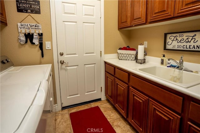 clothes washing area with washer and clothes dryer, cabinets, light tile patterned floors, and sink