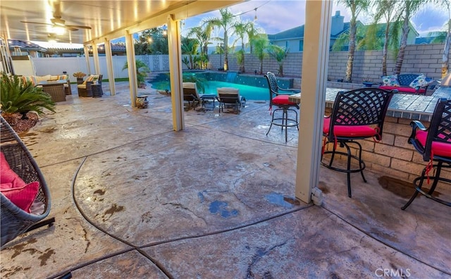 patio terrace at dusk featuring ceiling fan, a fenced in pool, and an outdoor hangout area