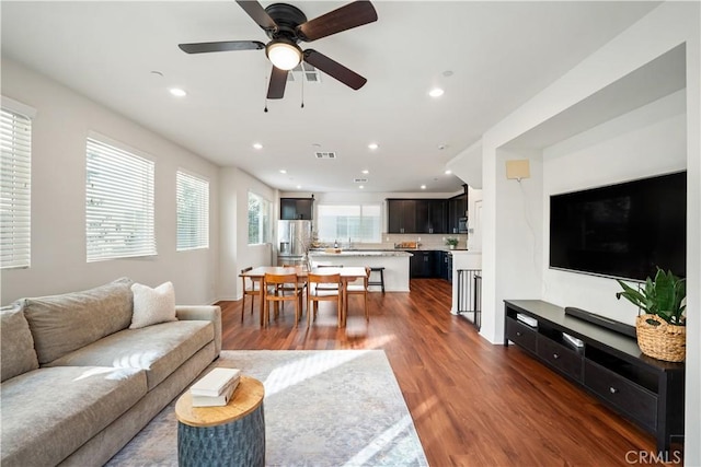 living room featuring ceiling fan and dark wood-type flooring