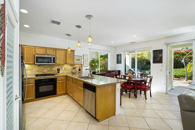 kitchen featuring kitchen peninsula, appliances with stainless steel finishes, a healthy amount of sunlight, sink, and pendant lighting