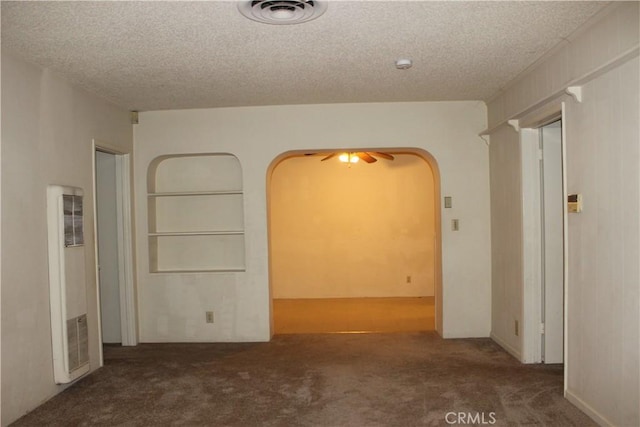 empty room with dark colored carpet, ceiling fan, and a textured ceiling