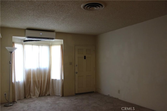 carpeted foyer with a wall unit AC and a textured ceiling