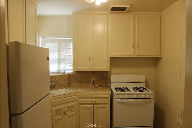 kitchen with decorative backsplash, white cabinetry, sink, and white appliances