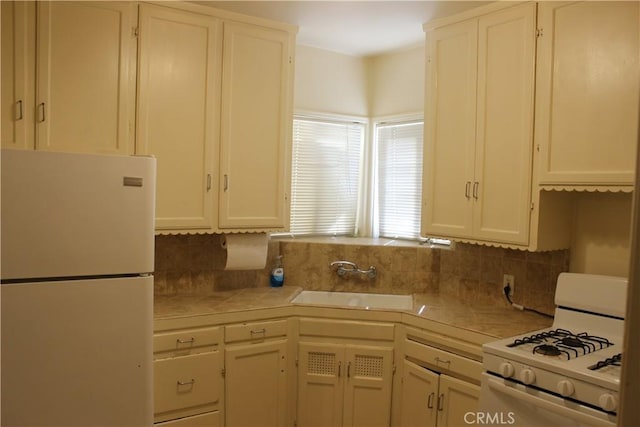 kitchen featuring tasteful backsplash, sink, white cabinets, and white appliances