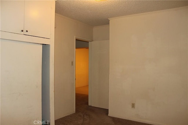 unfurnished bedroom featuring a textured ceiling, dark carpet, and crown molding