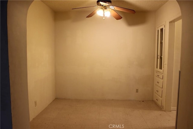 unfurnished room with ceiling fan and a textured ceiling