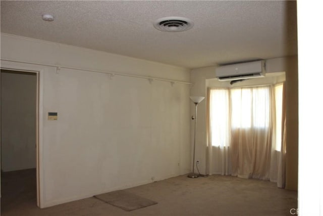 carpeted empty room with a wall mounted air conditioner and a textured ceiling