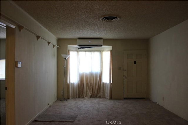 carpeted empty room featuring a textured ceiling and a wall unit AC