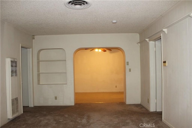 unfurnished room featuring ceiling fan, dark carpet, and a textured ceiling