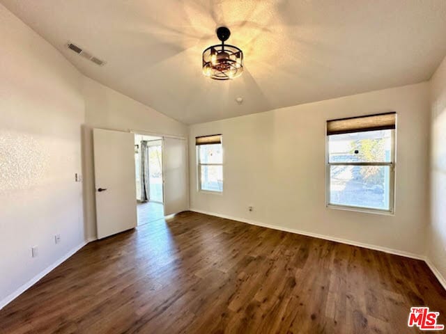 empty room with dark wood-type flooring and vaulted ceiling