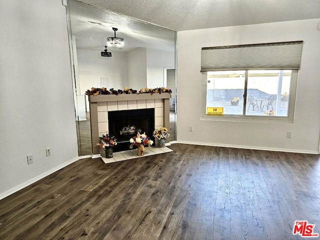 unfurnished living room with a tile fireplace, a textured ceiling, and dark hardwood / wood-style flooring