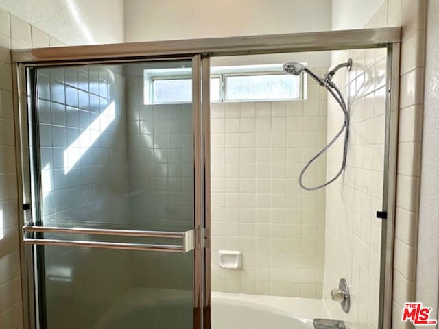 bathroom with bath / shower combo with glass door