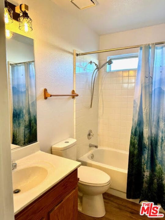 full bathroom featuring hardwood / wood-style flooring, vanity, toilet, and shower / bathtub combination with curtain