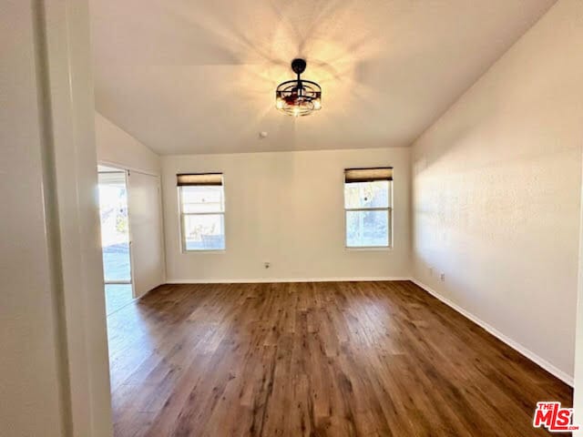 empty room featuring dark hardwood / wood-style flooring and vaulted ceiling