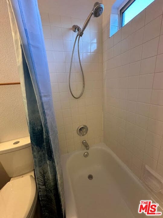 bathroom featuring shower / tub combo and toilet