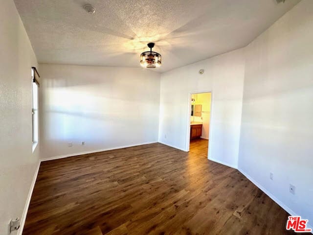 spare room with a textured ceiling and dark hardwood / wood-style floors