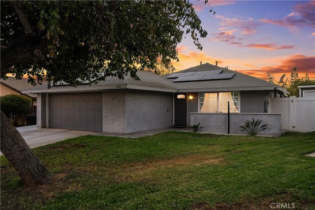 view of front of home with a lawn, solar panels, and a garage