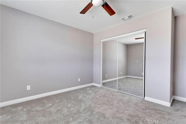 unfurnished bedroom featuring ceiling fan, a closet, carpet, and a textured ceiling