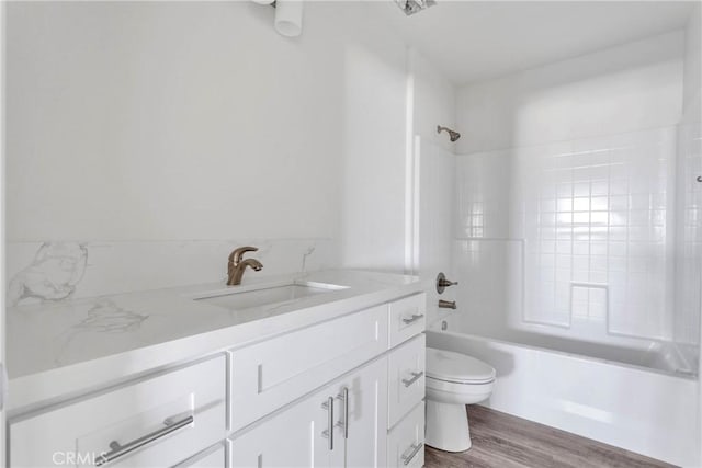 full bathroom with vanity, hardwood / wood-style floors, tiled shower / bath combo, and toilet