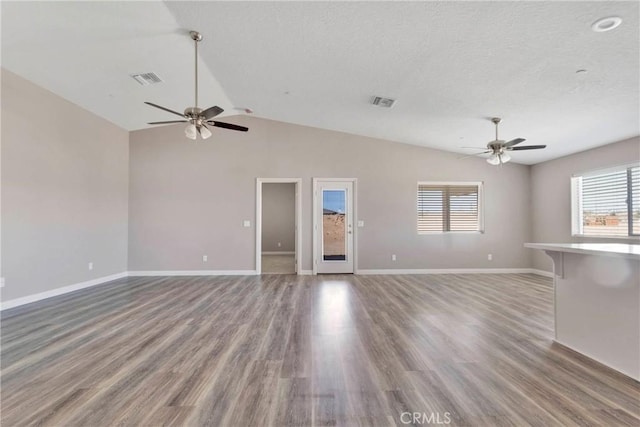 unfurnished living room featuring a textured ceiling, hardwood / wood-style flooring, ceiling fan, and lofted ceiling