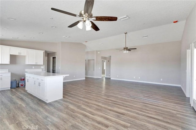 kitchen featuring white cabinetry, light hardwood / wood-style floors, and lofted ceiling