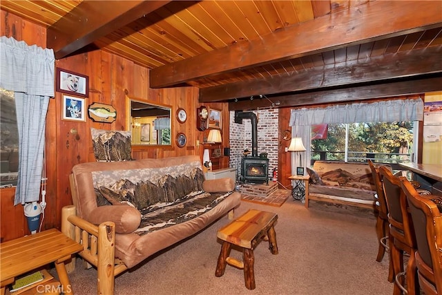 living room with wood walls, beam ceiling, a wood stove, and wood ceiling