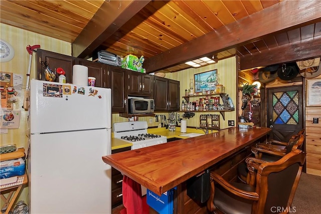 kitchen featuring white appliances, wooden ceiling, wooden walls, dark brown cabinets, and beam ceiling