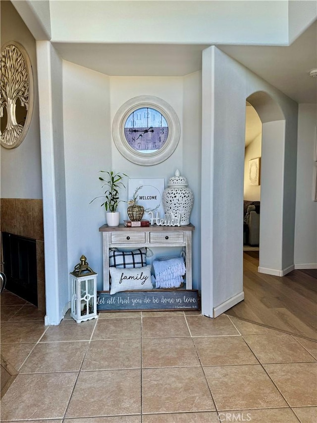 interior space featuring arched walkways, baseboards, and tile patterned floors