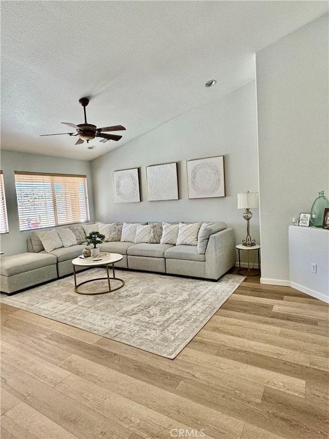 living area featuring lofted ceiling, ceiling fan, a textured ceiling, and wood finished floors