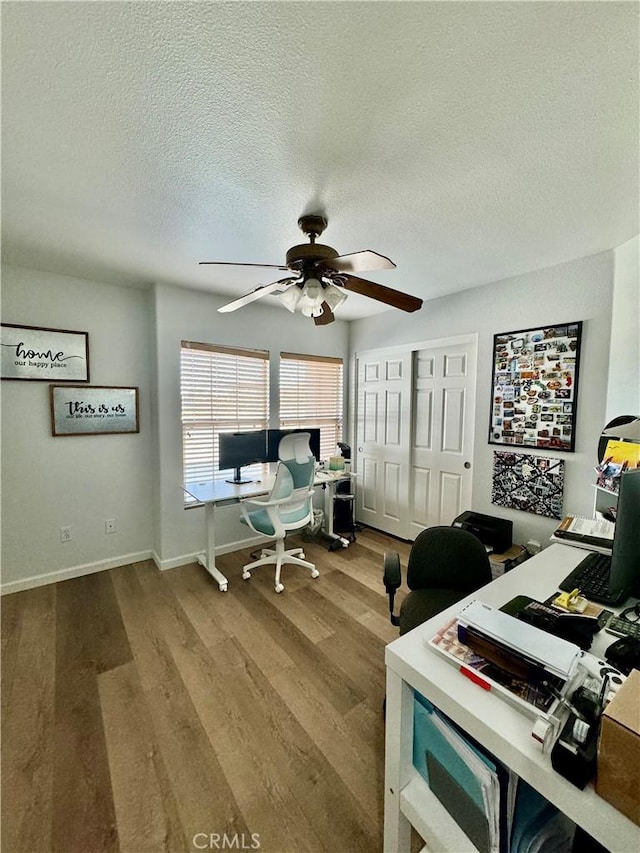 office space with ceiling fan, a textured ceiling, baseboards, and wood finished floors