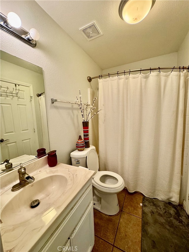 bathroom with tile patterned floors, vanity, toilet, and a textured ceiling