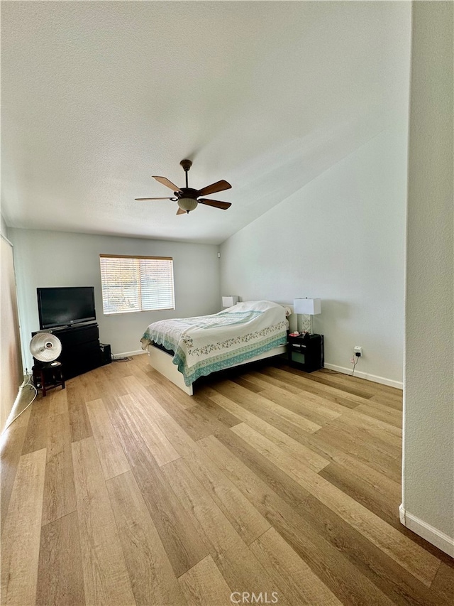 unfurnished bedroom with a textured ceiling, vaulted ceiling, light hardwood / wood-style flooring, and ceiling fan