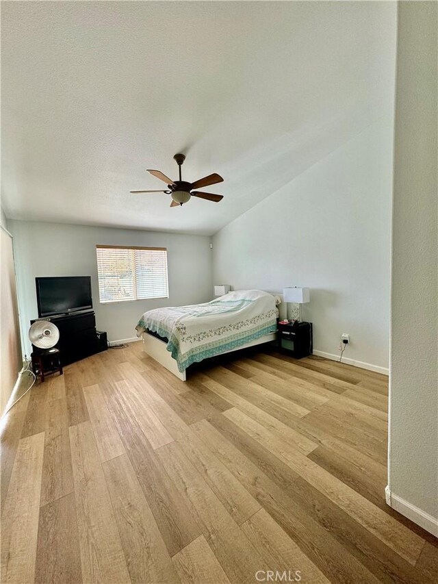 unfurnished bedroom with ceiling fan, a textured ceiling, baseboards, and wood finished floors