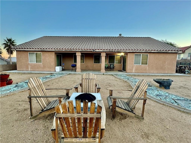 rear view of property with a patio area, an outdoor fire pit, a tile roof, and stucco siding