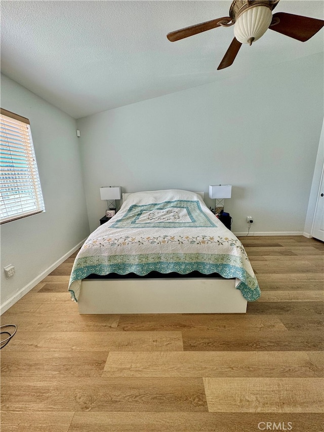 bedroom featuring a textured ceiling, light hardwood / wood-style flooring, ceiling fan, and lofted ceiling