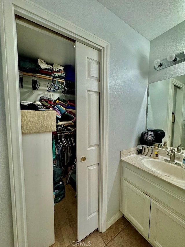 bathroom featuring tile patterned floors, a walk in closet, and vanity