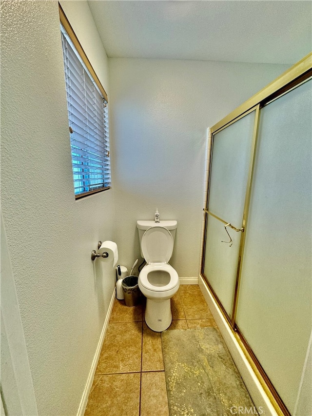 bathroom with tile patterned floors, walk in shower, and toilet