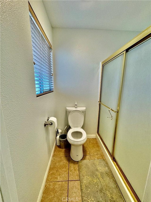 full bathroom featuring a stall shower, baseboards, toilet, and tile patterned floors