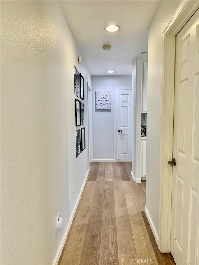 hallway featuring baseboards and light wood-style floors