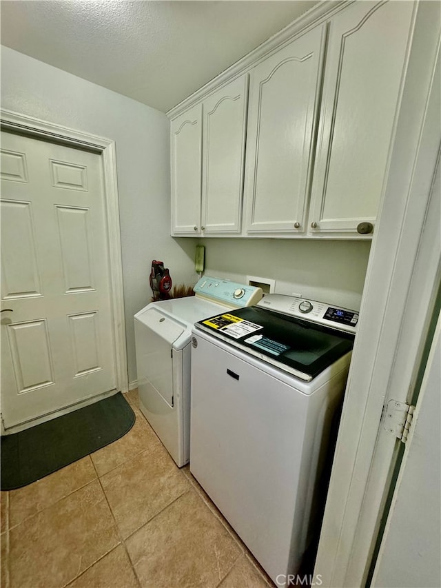 clothes washing area featuring cabinets, washing machine and dryer, and light tile patterned flooring