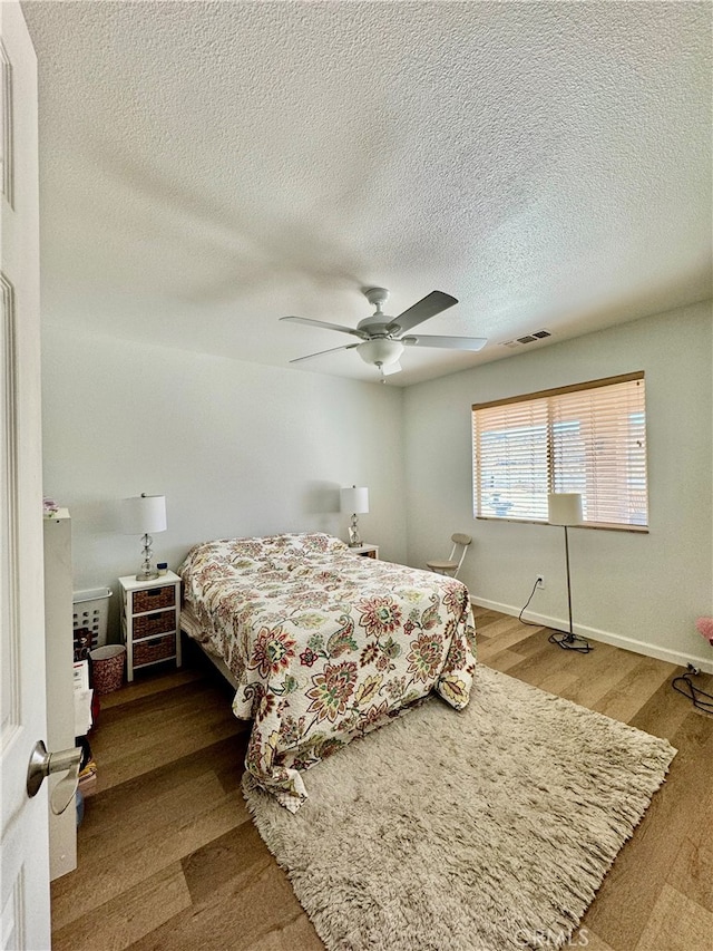 bedroom featuring ceiling fan, wood-type flooring, and a textured ceiling