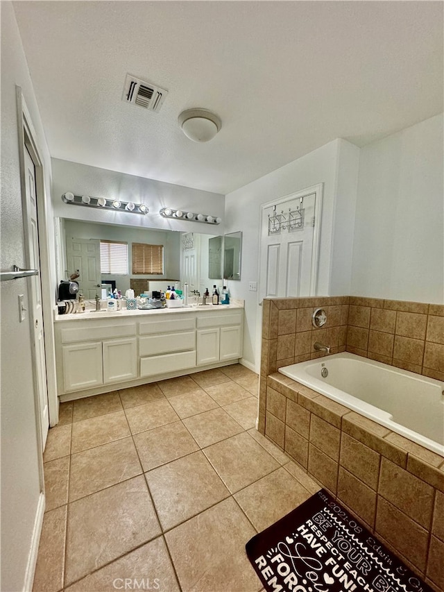 bathroom with tile patterned flooring, vanity, and a relaxing tiled tub