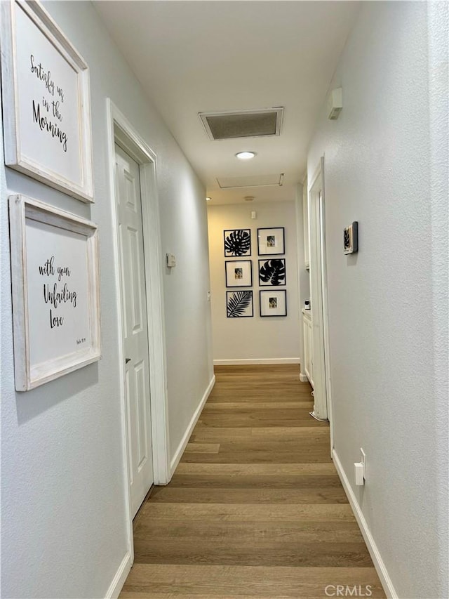 hallway with visible vents, baseboards, and wood finished floors