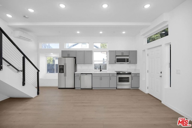 kitchen with gray cabinetry, stainless steel appliances, and light wood-type flooring