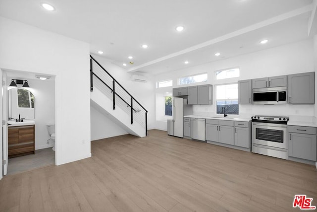 kitchen featuring gray cabinetry, sink, stainless steel appliances, and light wood-type flooring