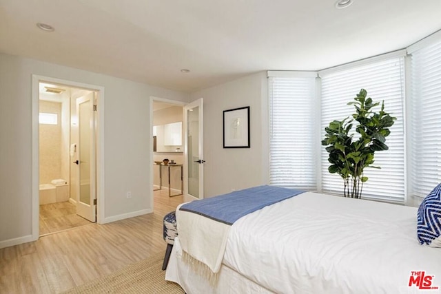 bedroom with light wood-type flooring and ensuite bathroom