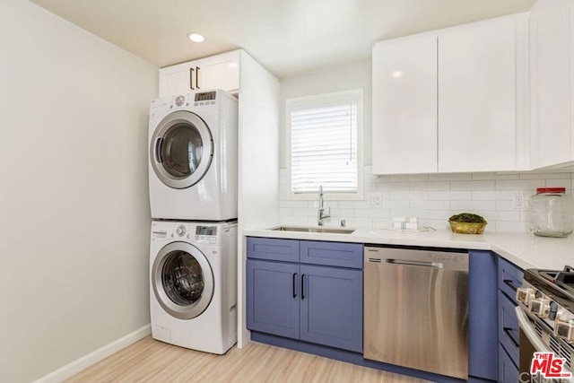 laundry area with light hardwood / wood-style flooring, stacked washer / drying machine, and sink