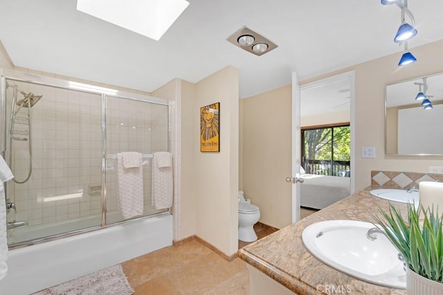 full bathroom featuring tile patterned floors, toilet, combined bath / shower with glass door, a skylight, and vanity